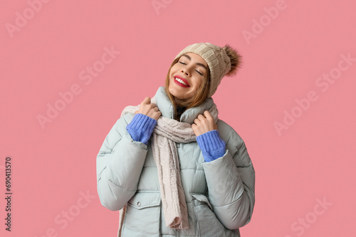 Beautiful young happy woman in winter clothes on pink background