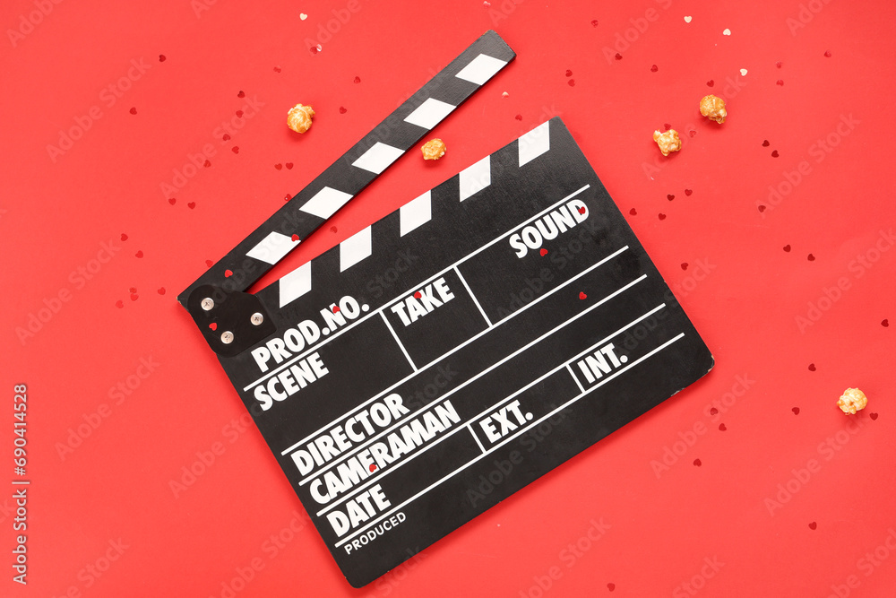 Movie clapper with popcorn and confetti on red background. Valentine's Day celebration