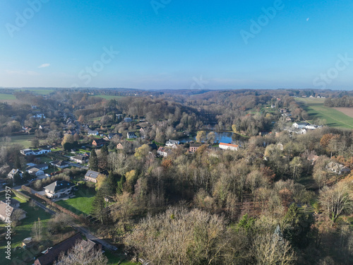 Aerial view of houses surrounded by forest and farmland in the country side area of Walloon, Belgium, Europe