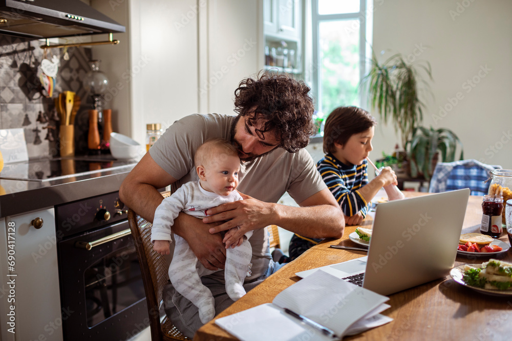 Busy Father Multitasking with Work and Children at Home Busy Father Multitasking with Work and Children at Home