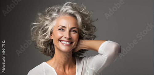 Portrait of very beautiful middle age woman with grey hair sliming to camera. 