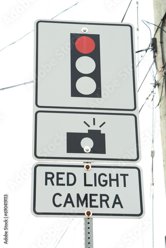 red light camera text sign with three atop each other with illustration of picture camera and red traffic light on metal post, portrait photo