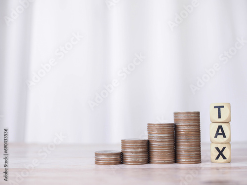 Wooden blocks with the word TAX and stack of coins. The concept of saving money for payment tax in future photo