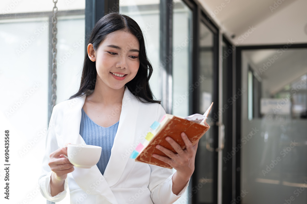 Portrait of a young beautiful Asian businesswoman holding a pencil and notebook, writing her work, she is thinking hard about her work. Portrait of a young beautiful Asian businesswoman holding a pencil and notebook, writing her work, she is thinking hard about her work.