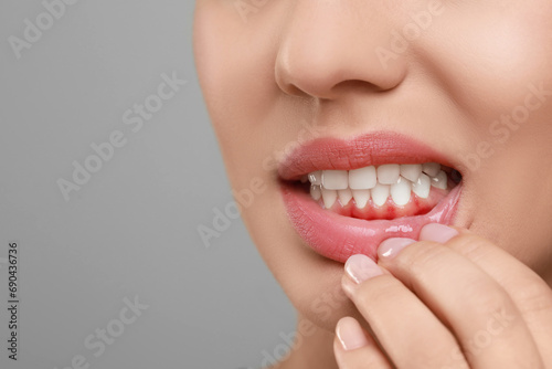 Woman showing inflamed gum on grey background, closeup. Space for text photo