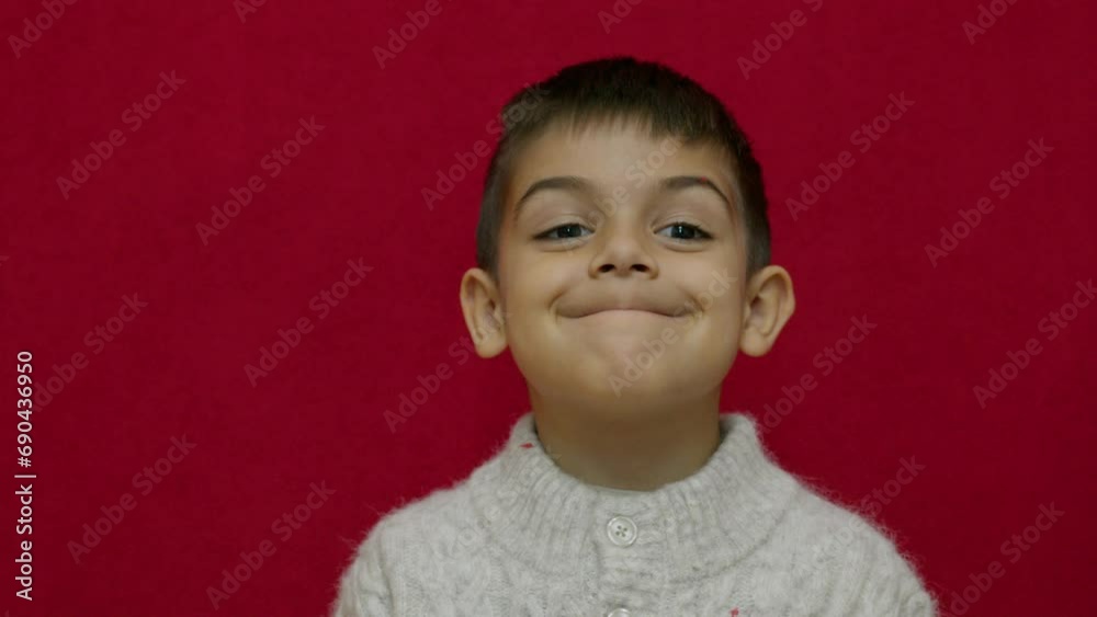 Cute child smiling and expressing his happiness with green happy emoyi. Isolated on red background, slow motion. High quality 4k footage Cute child smiling and expressing his happiness with green happy emoyi. Isolated on red background, slow motion. High quality 4k footage