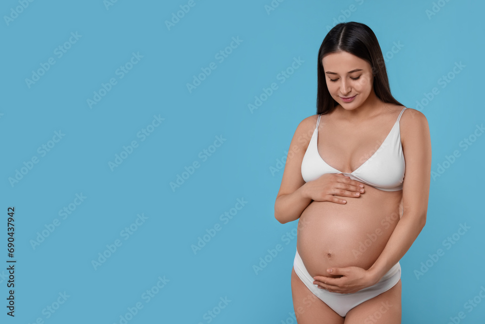 Beautiful pregnant woman in stylish comfortable underwear on light blue background, space for text Beautiful pregnant woman in stylish comfortable underwear on light blue background, space for text