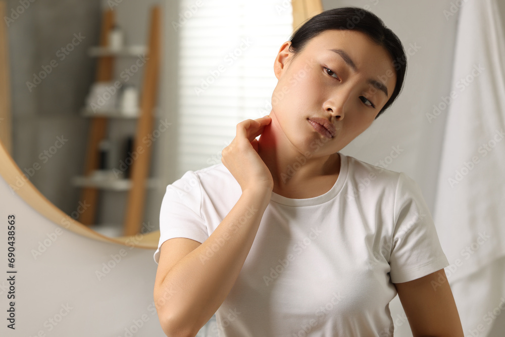 Suffering from allergy. Young woman scratching her neck near mirror in bathroom, space for text Suffering from allergy. Young woman scratching her neck near mirror in bathroom, space for text