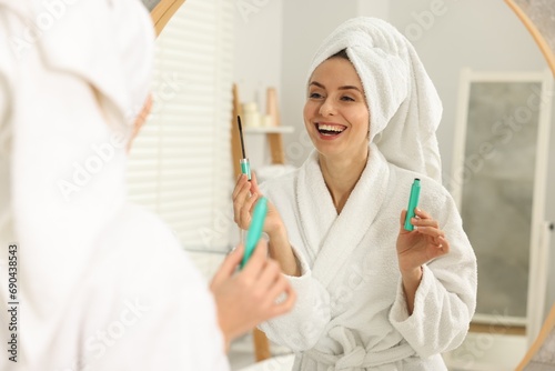 Beautiful woman with mascara near mirror in bathroom