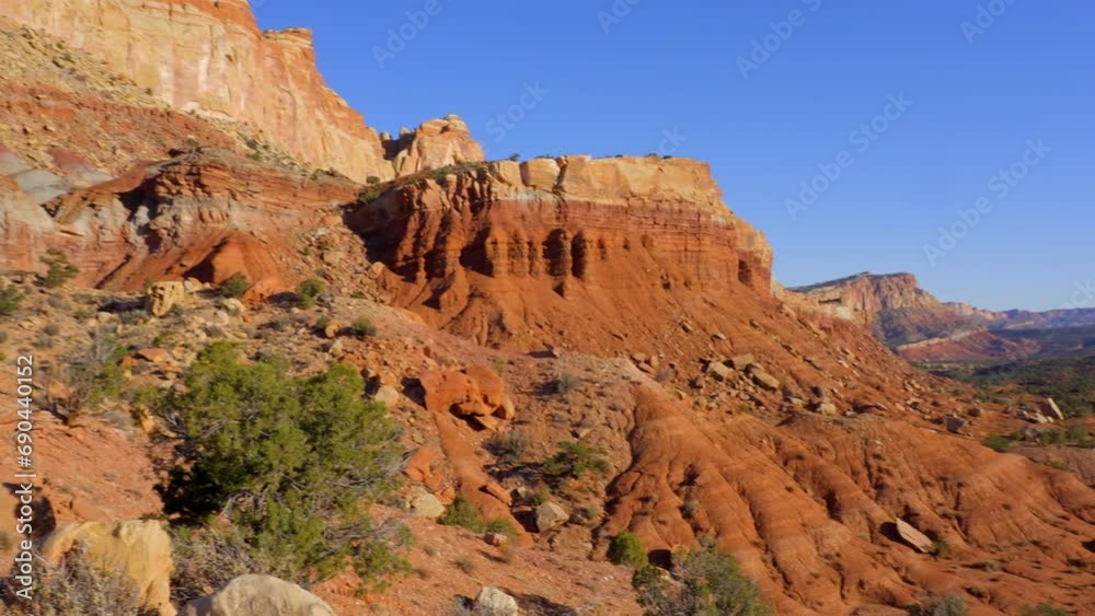 Establishing shot of mountains with red rocks background in Fruita Scenic Road, Capital Reef National Park, Utah, North America. Day time on October 2023. Still camera view. ProRes 422 HQ. Establishing shot of mountains with red rocks background in Fruita Scenic Road, Capital Reef National Park, Utah, North America. Day time on October 2023. Still camera view. ProRes 422 HQ.