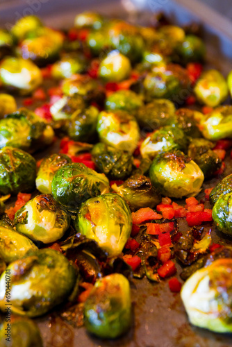 Fototapeta Naklejka Na Ścianę i Meble -  Roasted Brussels Sprouts and Red Bell Peppers in Warm Lighting Close-Up