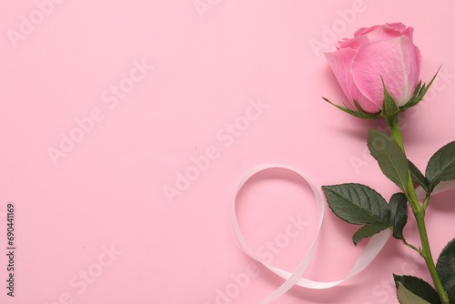 Beautiful rose and ribbon on pink background, top view. Space for text