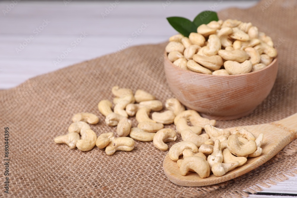 Tasty cashew nuts and green leaves on table, closeup. Space for text Tasty cashew nuts and green leaves on table, closeup. Space for text