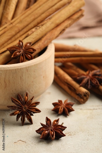Bowl with cinnamon sticks and star anise on light table, closeup