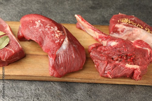 Pieces of raw beef meat and spices on grey textured table photo