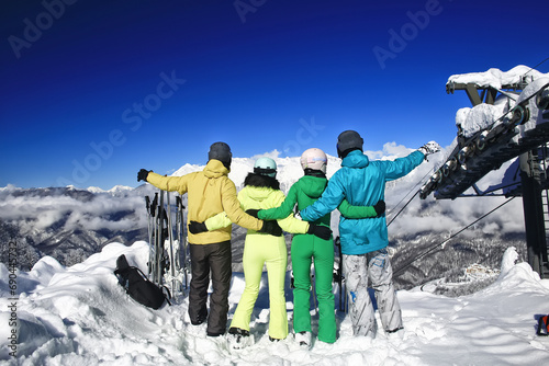 group of four friends at a ski resort posing on a slope in winter