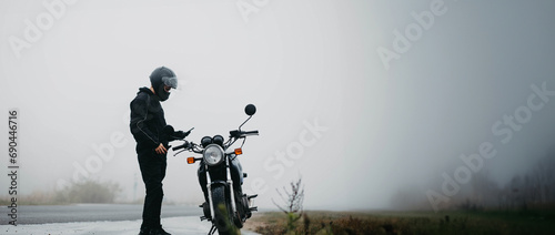 male motorcyclist with a motorcycle on a foggy asphalt road.