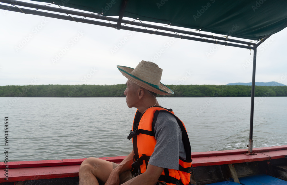 An adult Asian traveler sitting on long tail boat. Sustainability travel concept. An adult Asian traveler sitting on long tail boat. Sustainability travel concept.