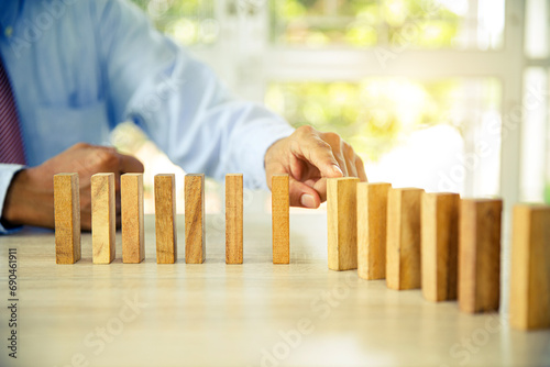 Hand to stop wooden block prevent not falling domino concepts of financial risk management and strategic planning and business challenge plan or safety insurance.