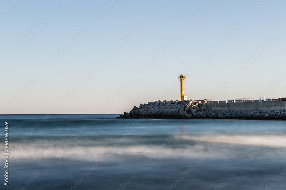 Beach scenery with a lighthouse and breakwater

