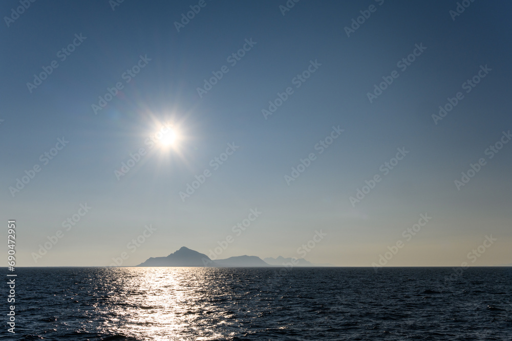 Bright sun, complete with sunburst, in the sky reflecting light across the arctic ocean, mountain range on the horizon
Bright sun, complete with sunburst, in the sky reflecting light across the arctic ocean, mountain range on the horizon