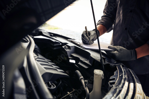 Hand auto mechanic using checklist after service repairing car engine problem concepts of check and inspection car care maintenance and servicing.