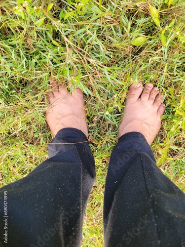 Overhead view of anonymous man standing barefoot on green grass in park during hiking