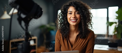 Public speaking online. Multiracial lady training teacher through recorded video lecture at home office with digital camera. Young Indian female vlogger creating video content.