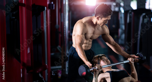 Asian trainer is introducing the use of a barbell to a student in the gym