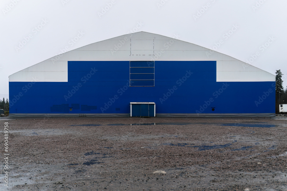 Obraz premium Blue and white sports arena building with gravel parking