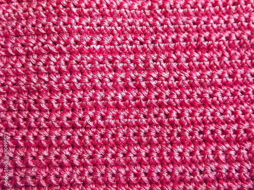 The process of crocheting pink yarn on a purple background