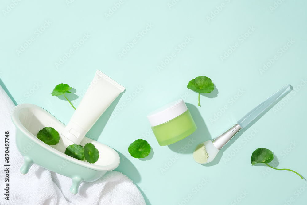 An unlabeled skincare set is displayed with fresh pennywort and props against a light blue background. Gotu kola helps reduce inflammation and redness caused by problems such as acne.