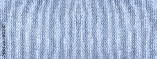 Background. The texture of knitted blue fabric. Smooth knitted surface. Banner. Long. Close-up. Woolen threads of blue color. Knitted product. Texture. View from above. Copy space