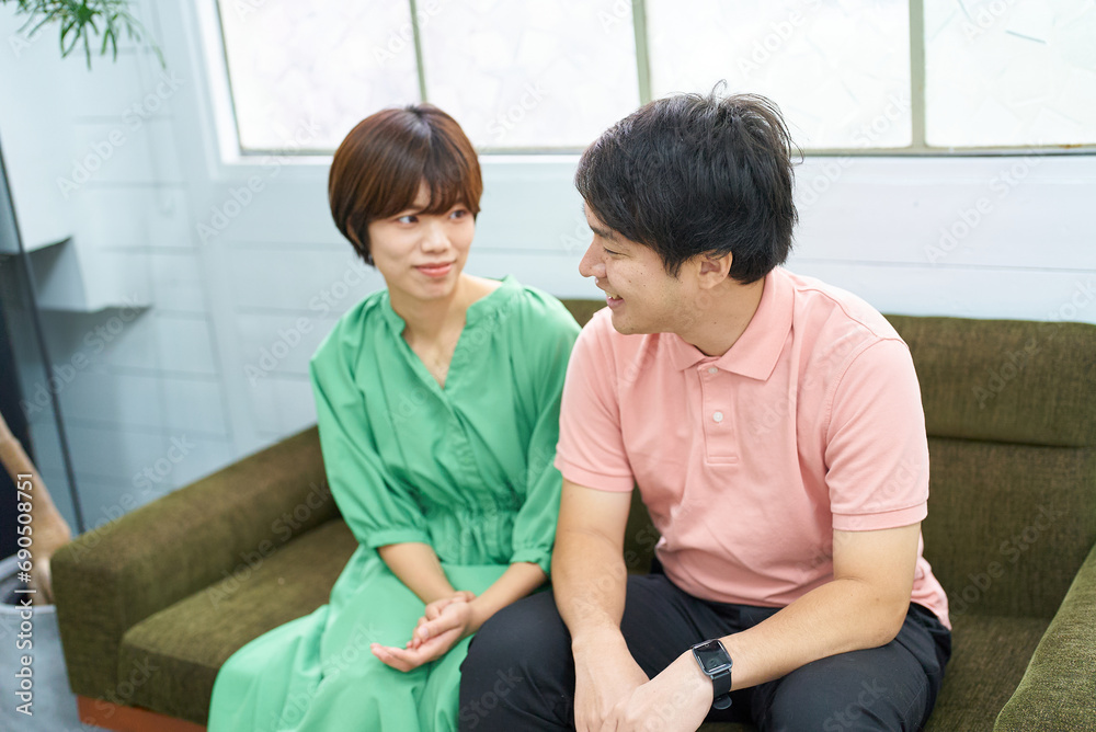 ソファに座って会話する若い男女