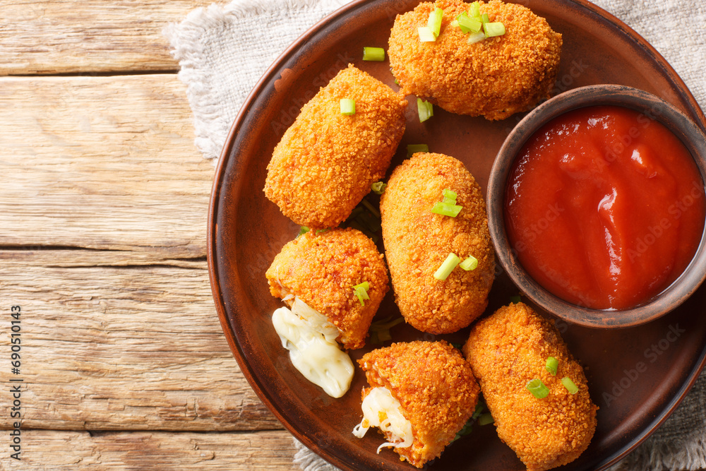 Naklejka premium Italian Rice balls stuffed with mozzarella cheese and deep fried closeup on the plate on the table. Horizontal top view from above