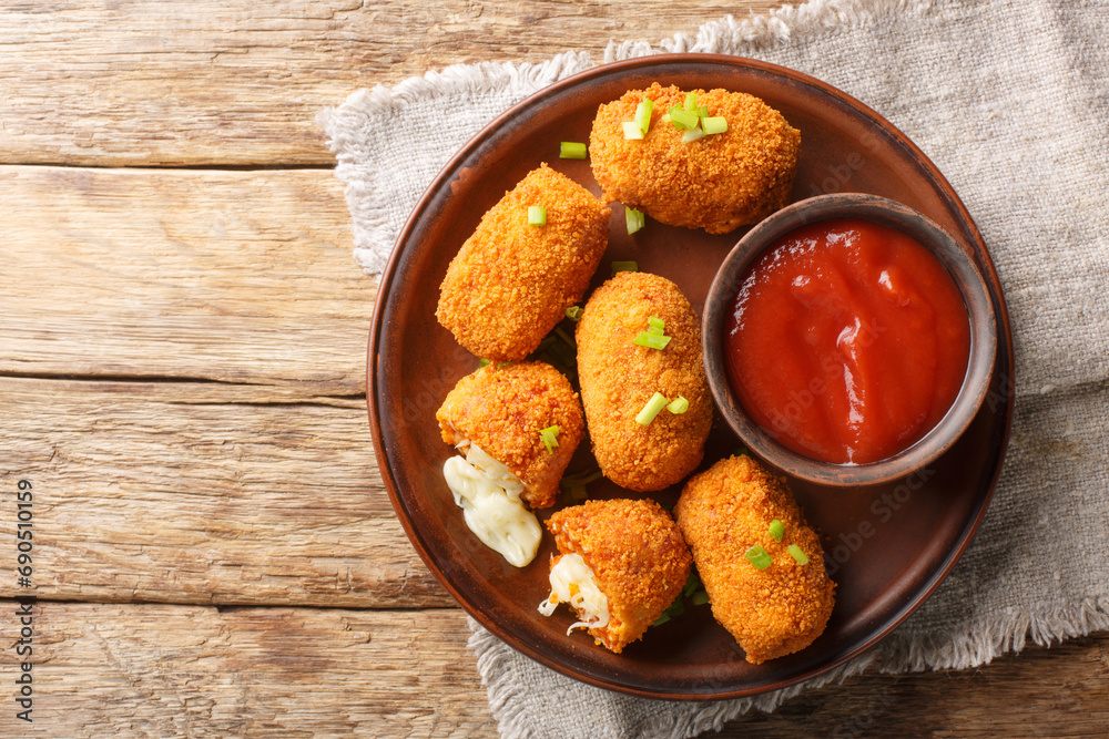 Suppli al Telefono are made with a simple sauce, rice and fresh mozzarella closeup on the plate on the table. Horizontal top view from above