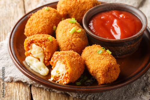Suppli al telefono Italian snacks consisting of rice with tomato sauce filled with mozzarella, soaked in eggs, coated with bread crumbs and deep-fried closeup on the plate on the table. Horizontal