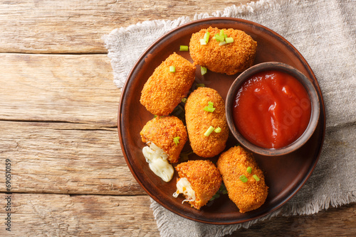 Suppli al Telefono are made with a simple sauce, rice and fresh mozzarella closeup on the plate on the table. Horizontal top view from above photo