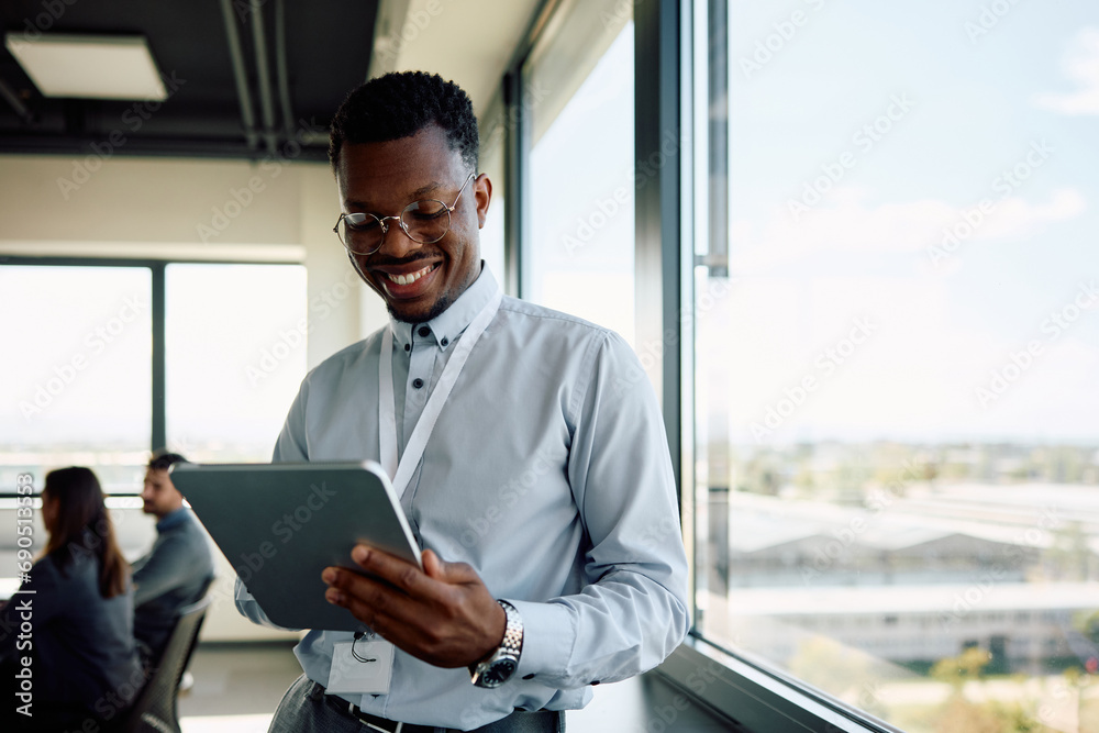Fototapeta premium Happy black businessman working on digital tablet in office.
