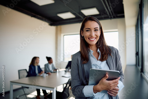 Young happy businesswoman using digital tablet in meeting room and looking at camera. photo