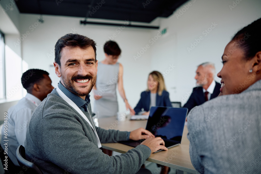 Happy businessman using laptop during meeting and looking at camera. Happy businessman using laptop during meeting and looking at camera.