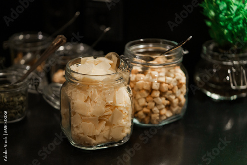 Close up of glass jars with pieces of parmesan cheese on dark background