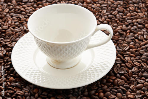 Top view of empty white coffee cup place on surface many roasted coffee beans background.