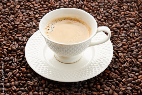 Top view of coffee in white cup place on surface many roasted coffee beans background.