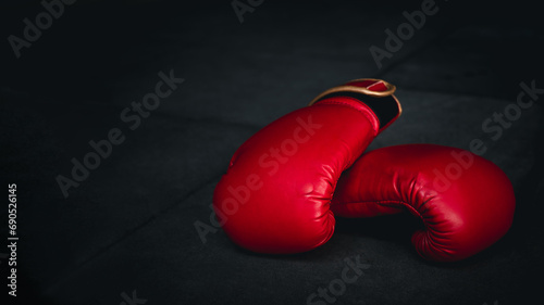 red boxing glove on boxing ring in gym with dark black background. Fight sport concept © Bordinthorn