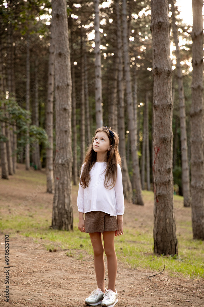 A little girl dressed in elegant clothes posing in the park. A little girl dressed in elegant clothes posing in the park.