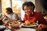 Happy African American mature woman at dining table during family Thanksgiving dinner.