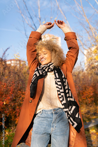 portrait latin girl blonde curly hair dancing happy in park autumn colors