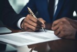 Office employee, company director writes on paper at the table. Male businessman signs a document, close-up. Concept: signing a contract, insurance, notary agreement