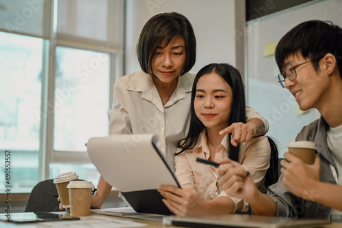 Professional senior businesswoman analyzing marketing data with younger colleagues at office.